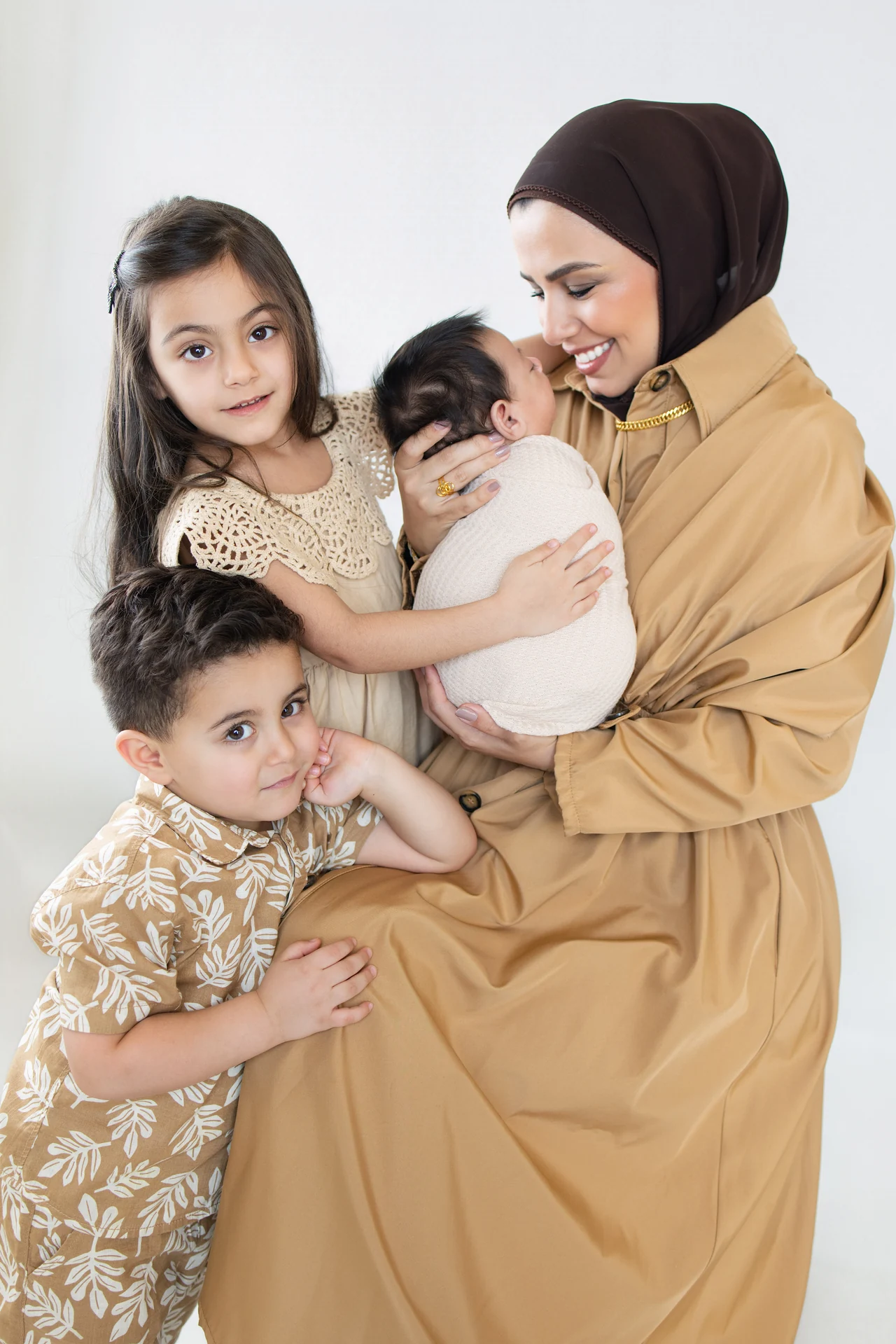 A mother holding her newborn with two children in a TALA family portrait