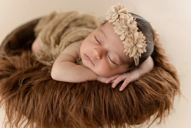 Sleeping baby on a warm brown texture with a floral headband